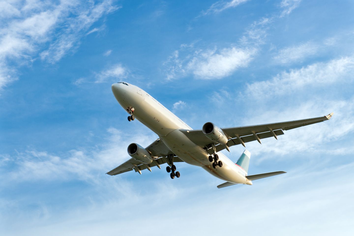 An airplane with its landing gear extended navigates the blue sky adorned with scattered clouds, resembling a dynamic content widget in motion.